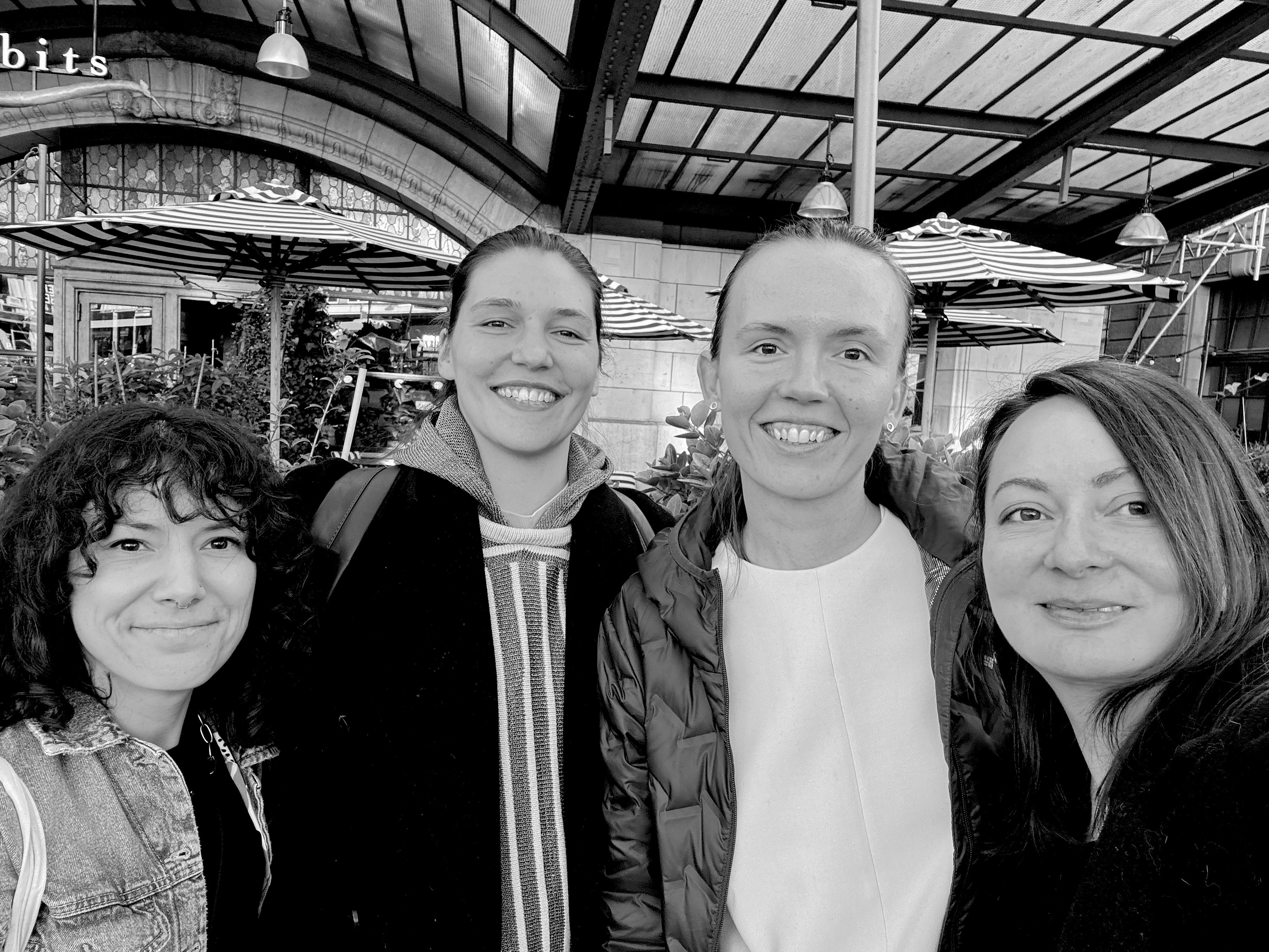 Black and white image of people working at a table with laptops, showing hands gesturing during discussion of digital content displayed on screens, with fabrica® logo in the corner.