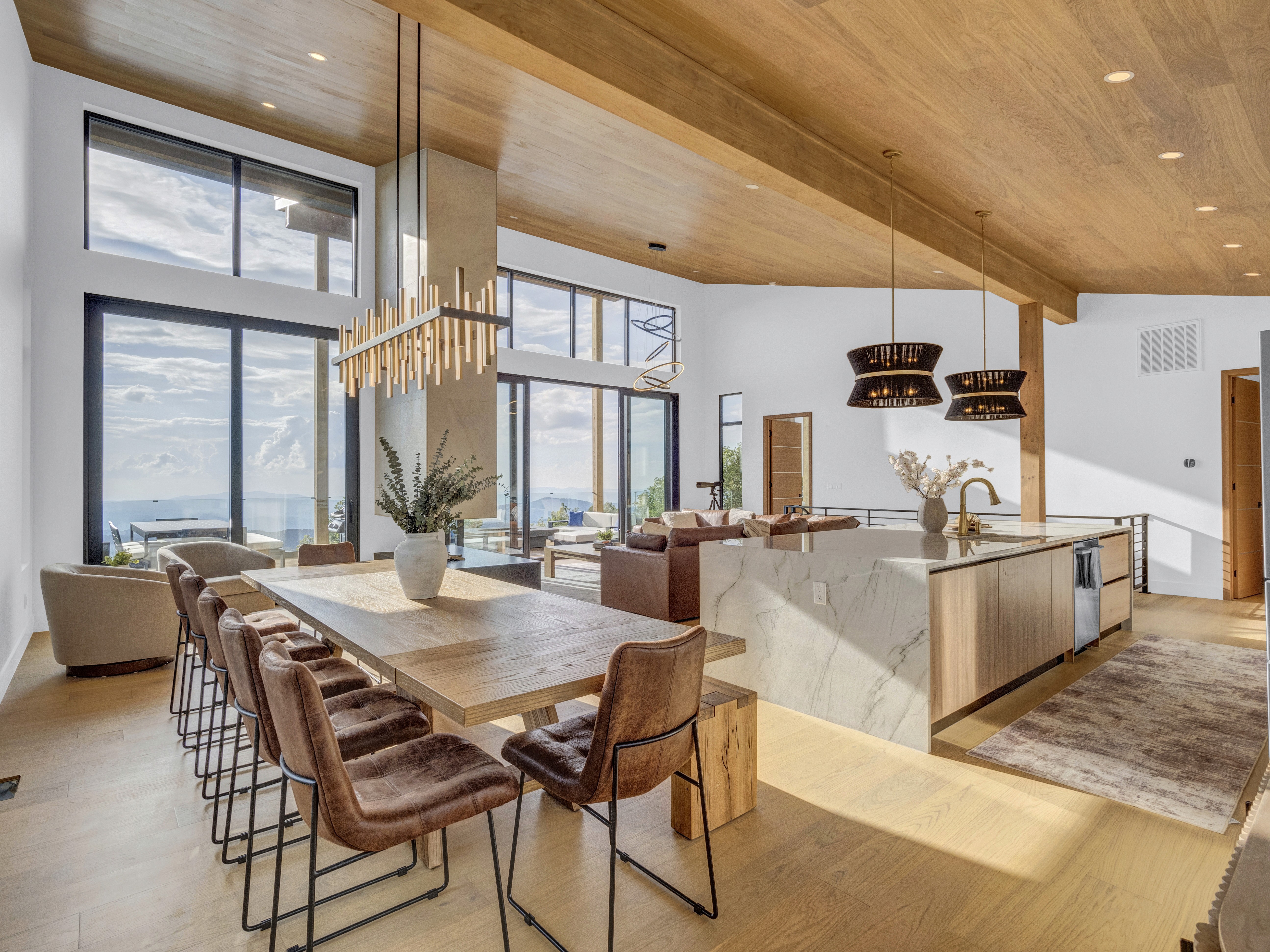 View from the kitchen island showing the open-concept layout leading toward floor-to-ceiling mountain vistas