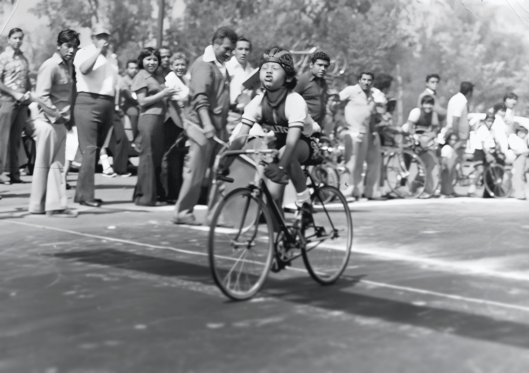 Marco Navarro niño en carrera ciclista infantil años 70, cruzando meta frente a espectadores en blanco y negro.