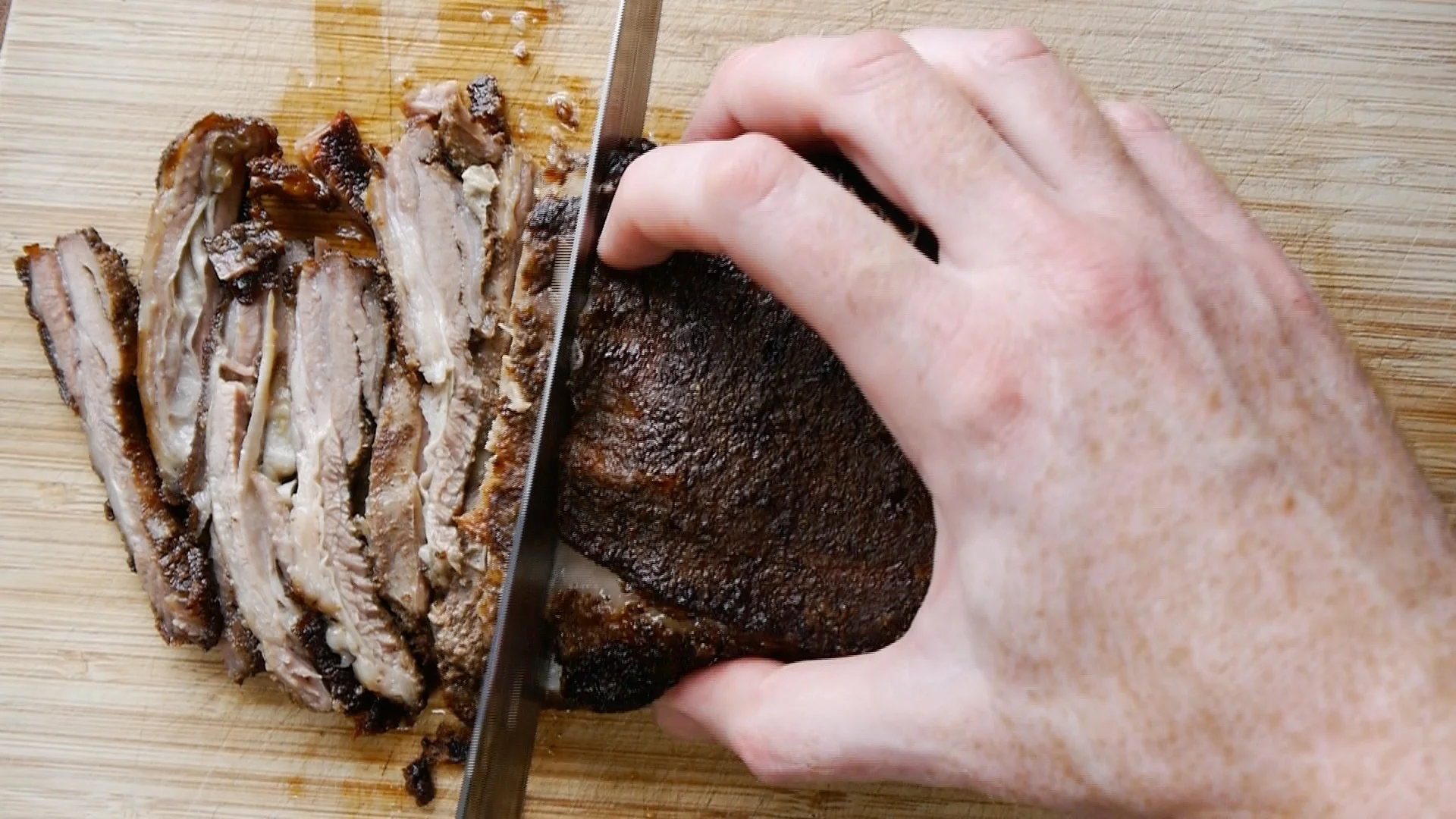 Cooked lamb being sliced with knife