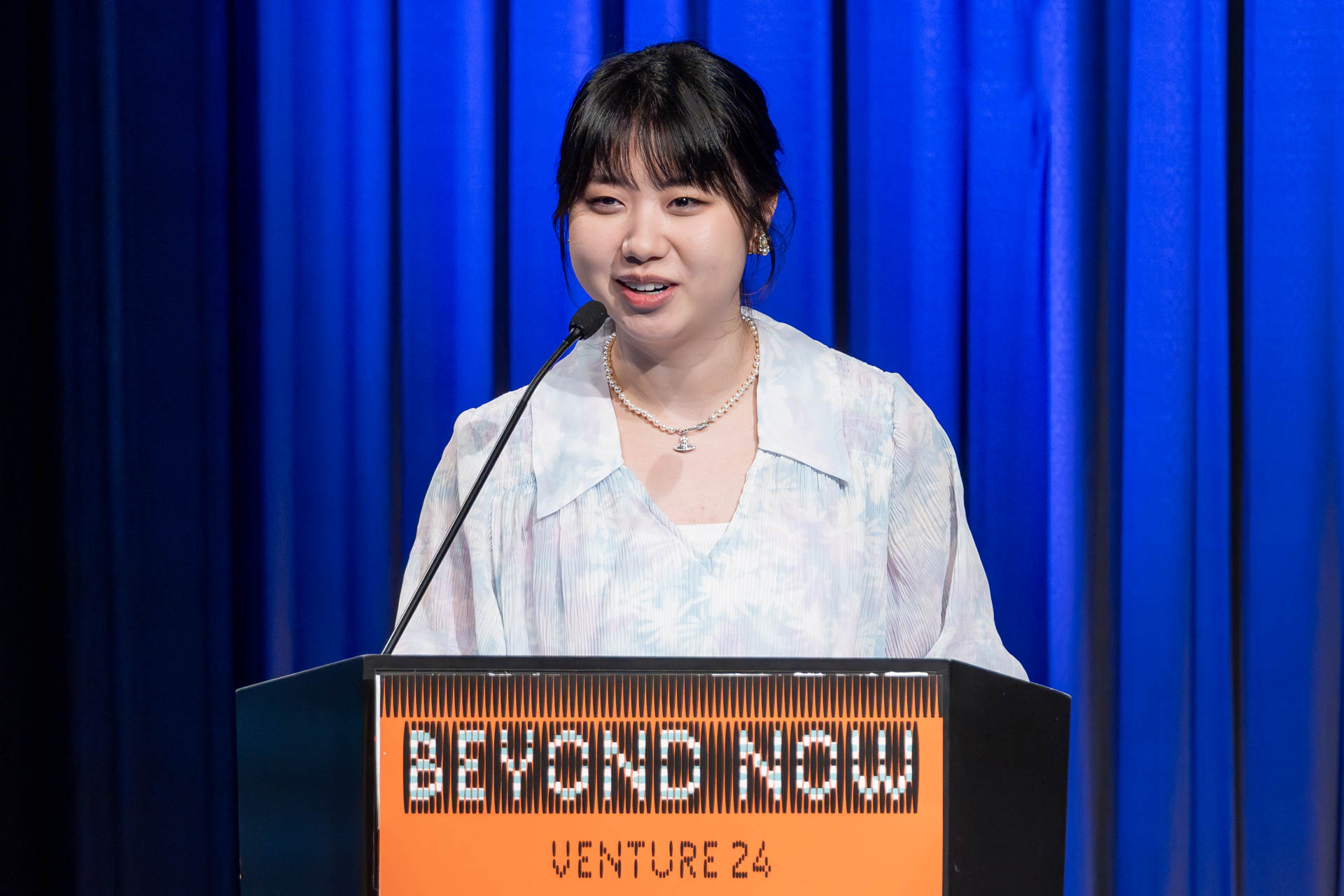 a student at a podium presenting a project in a Theatre