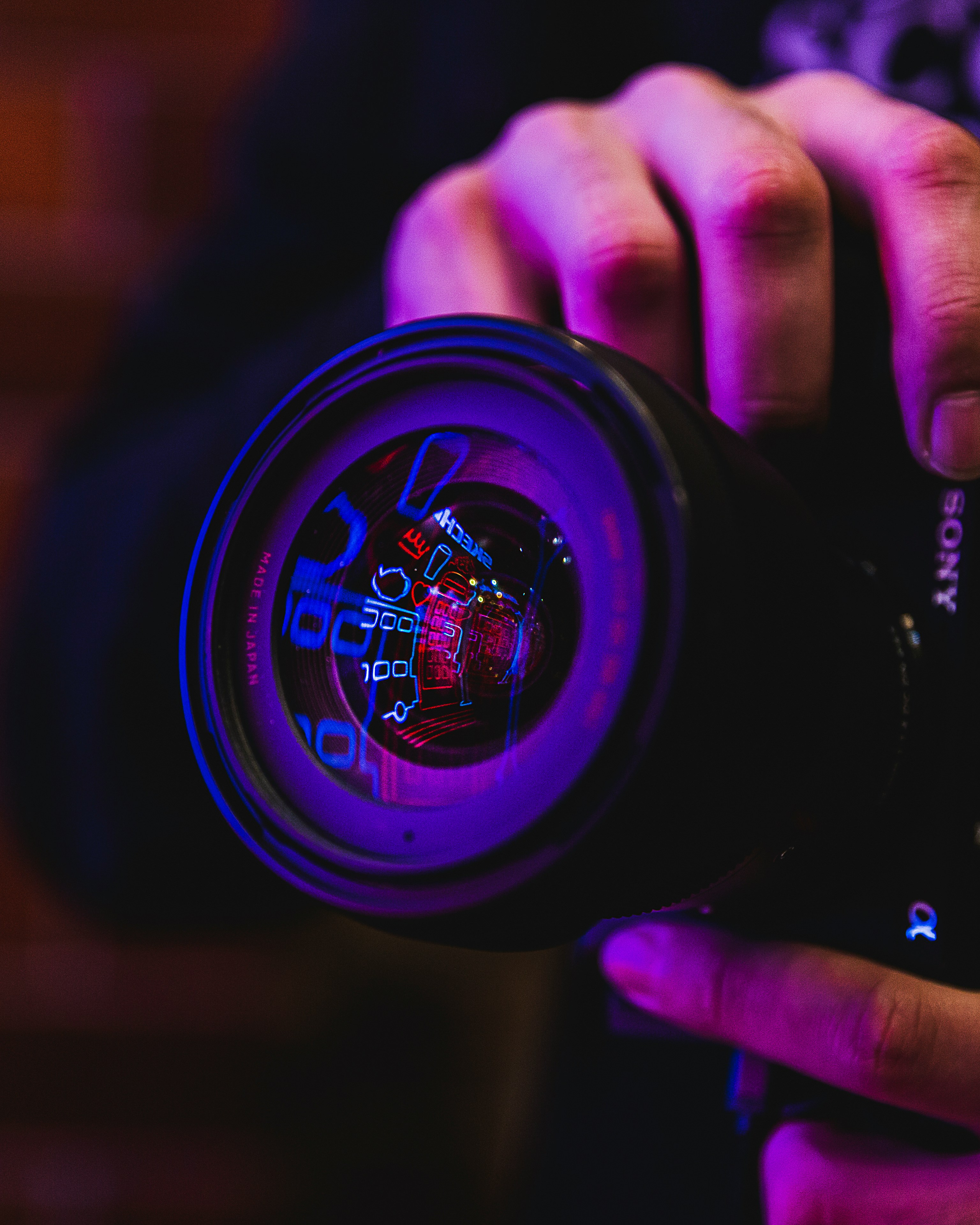 A camera lens reflecting neon lights