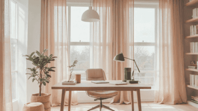 Minimalist home office with soft pink curtains, wooden desk, ergonomic chair, and warm natural lighting — ideal for a calm and budget-friendly remote work environment.