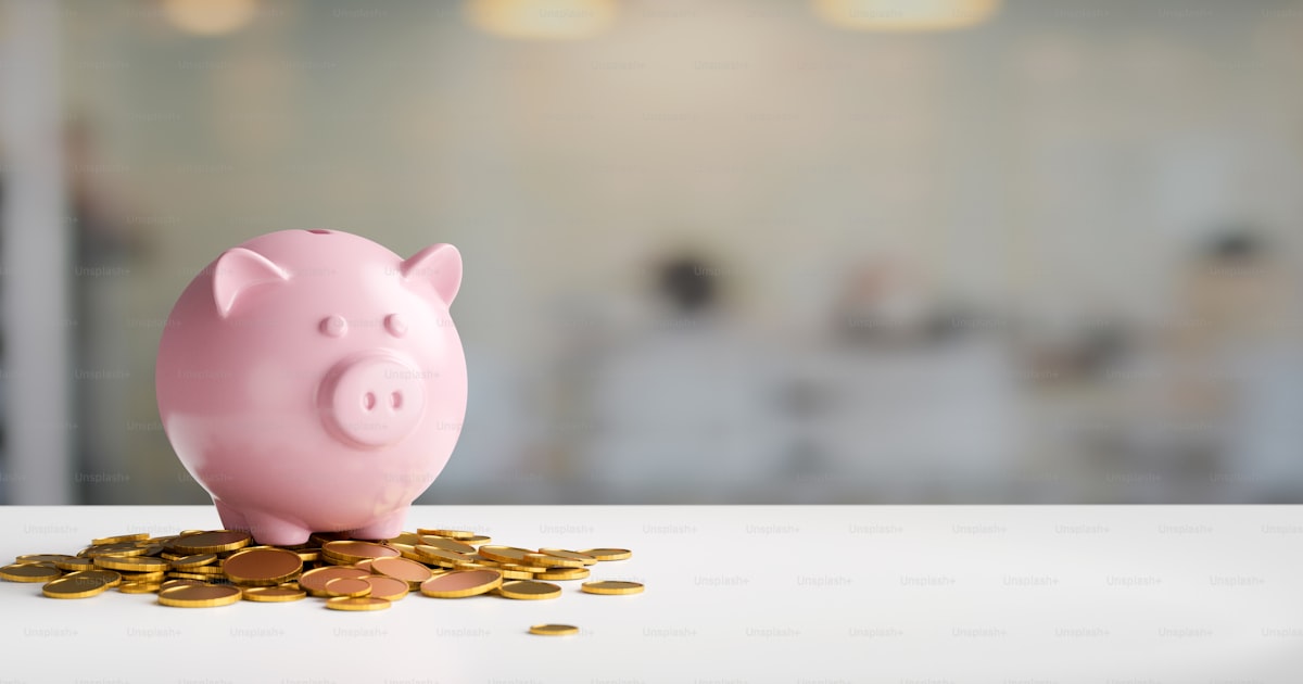 A pink piggy bank and coins on a clean white desk illustrating digital savings goals.