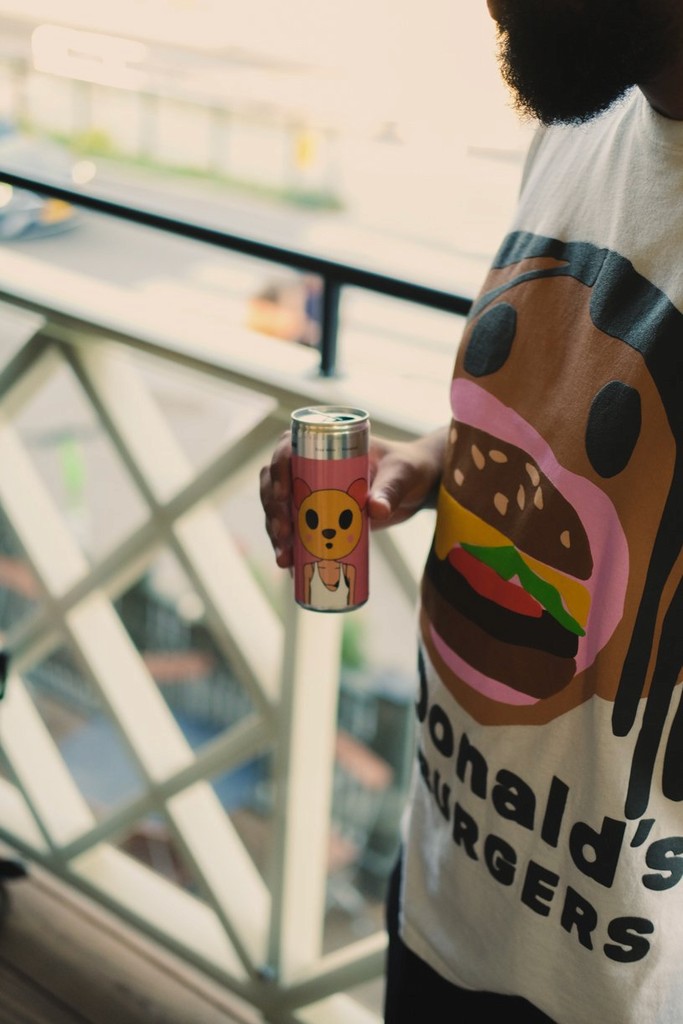 Person holding a can with a cartoon character of a bear wearing a pink hat.