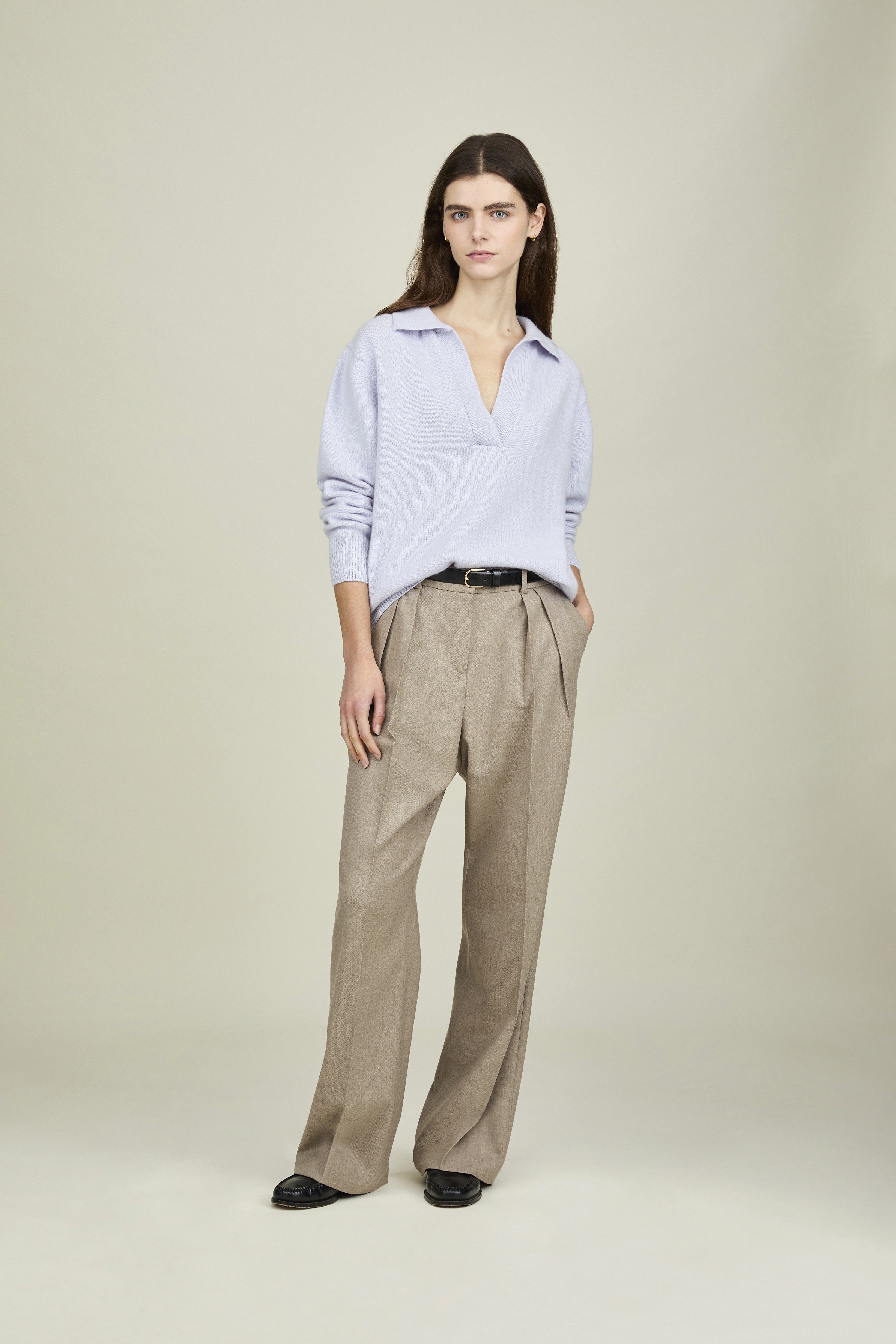 Dans le lookbook de la marque Sunspel, une femme porte une chemise bleu ample et un pantalon large beige