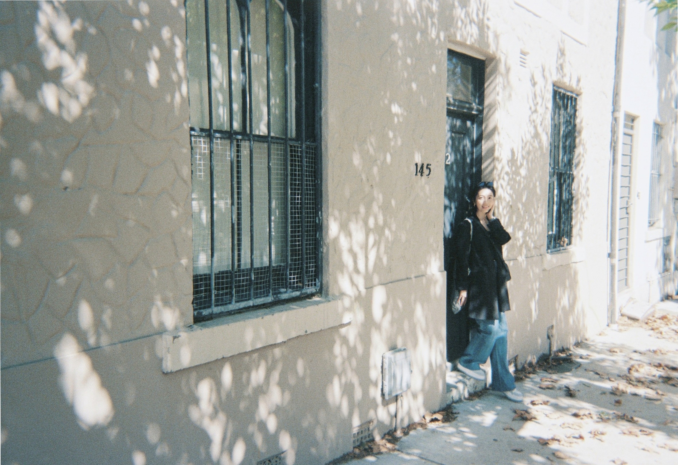 Portrait of a woman with slicked-back hair wearing a green turtleneck, posed against a dark green background with studio lighting.