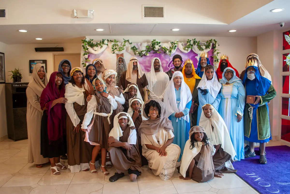 Church members in biblical-era costumes pose together after the Resurrection Sunday production at Peace Apostolic Church, with women in colorful robes and head coverings filling the sanctuary stage.