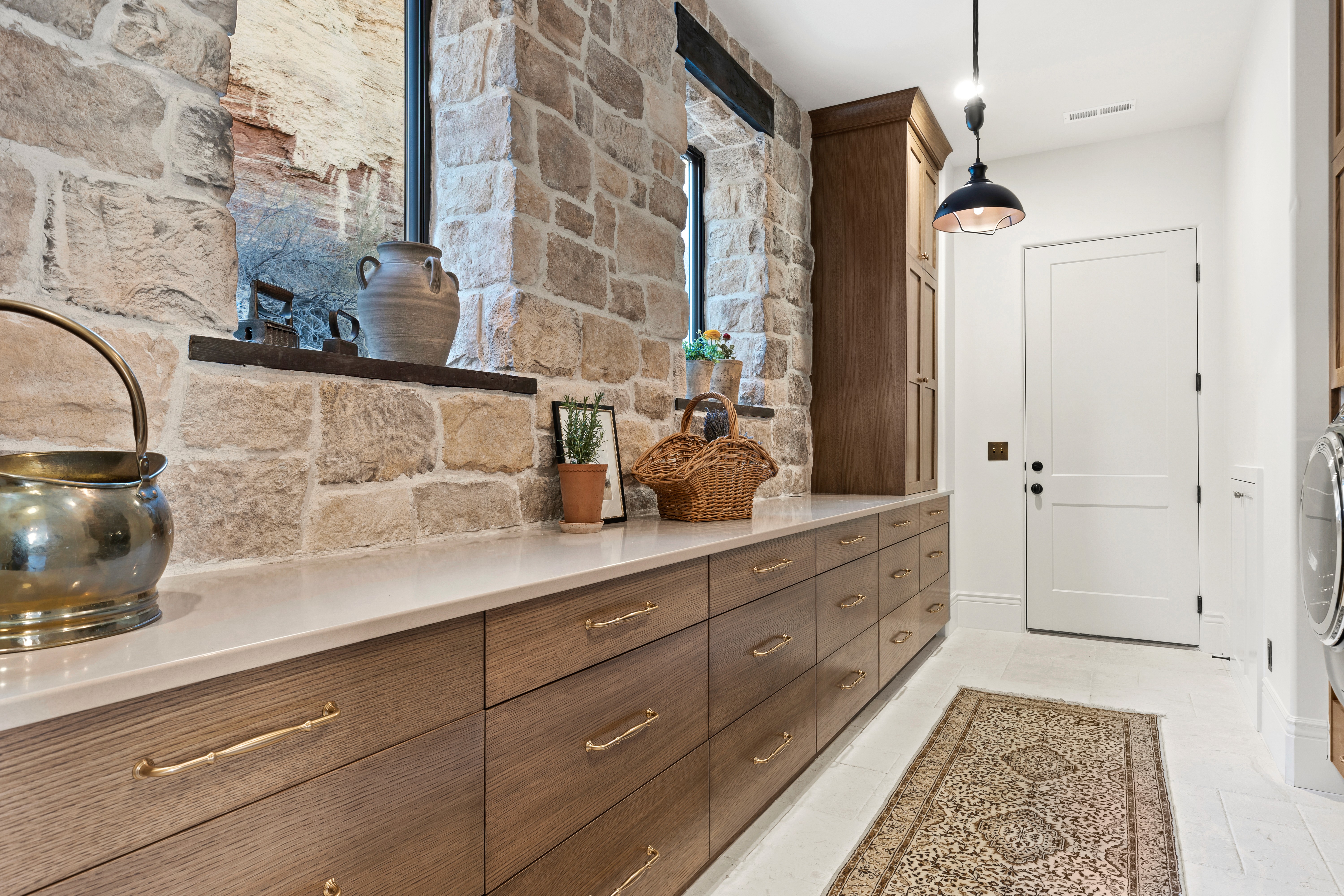 Butler's pantry with a stone accent wall, wood cabinets, and gold finishes in a custom home in Rockville, Utah.