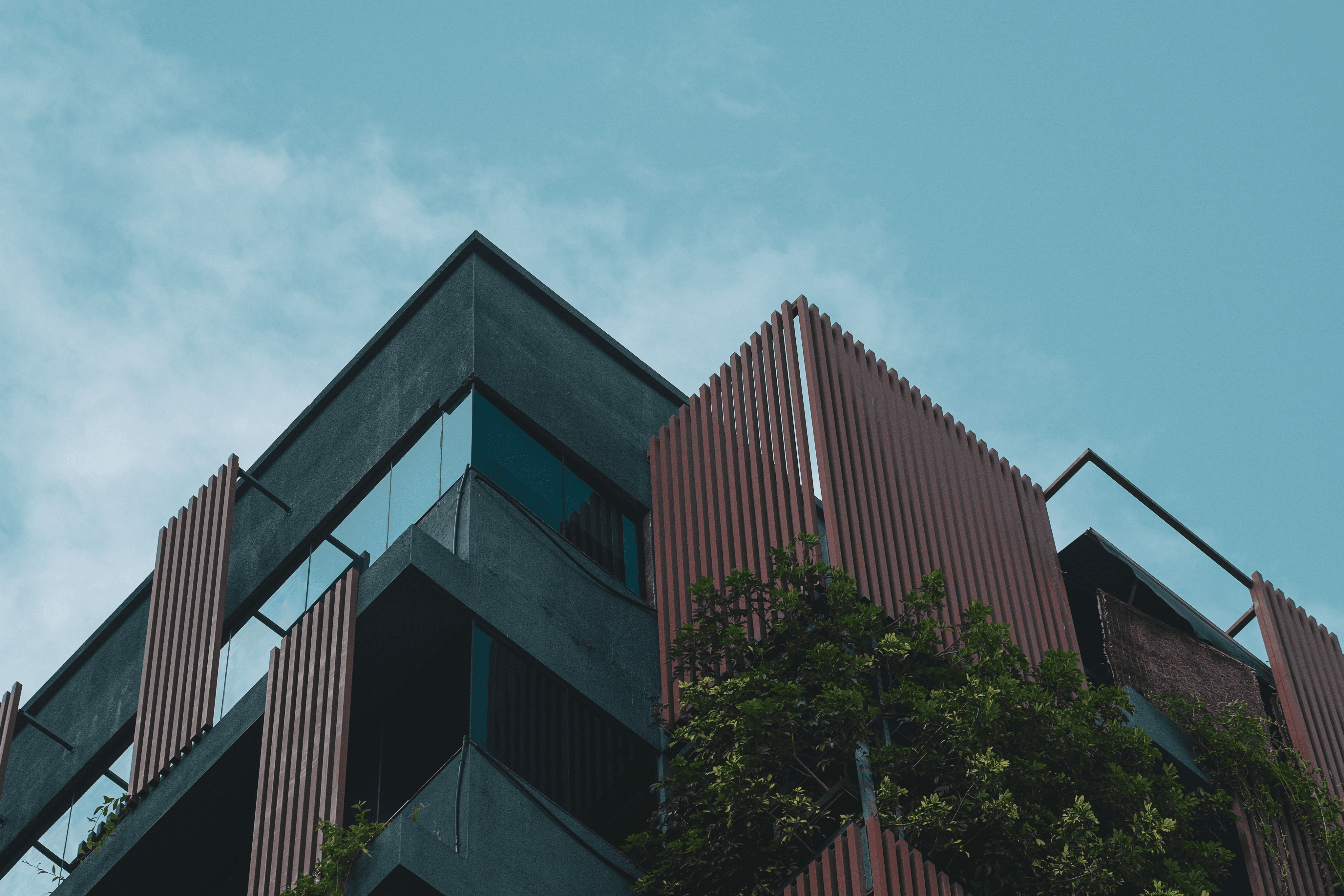 A tall building with a window and some bushes.