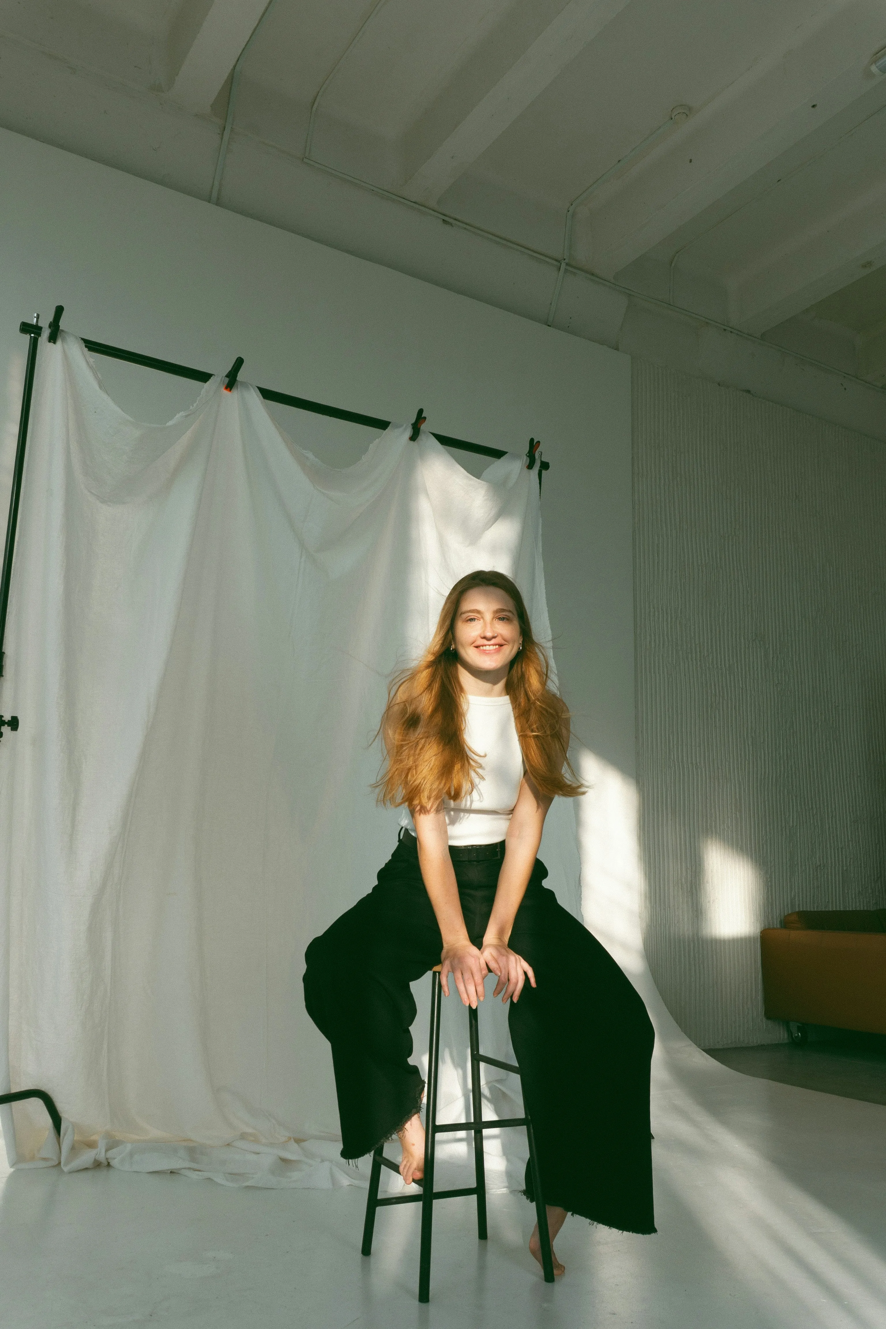 A smiling woman poses in a bright studio.