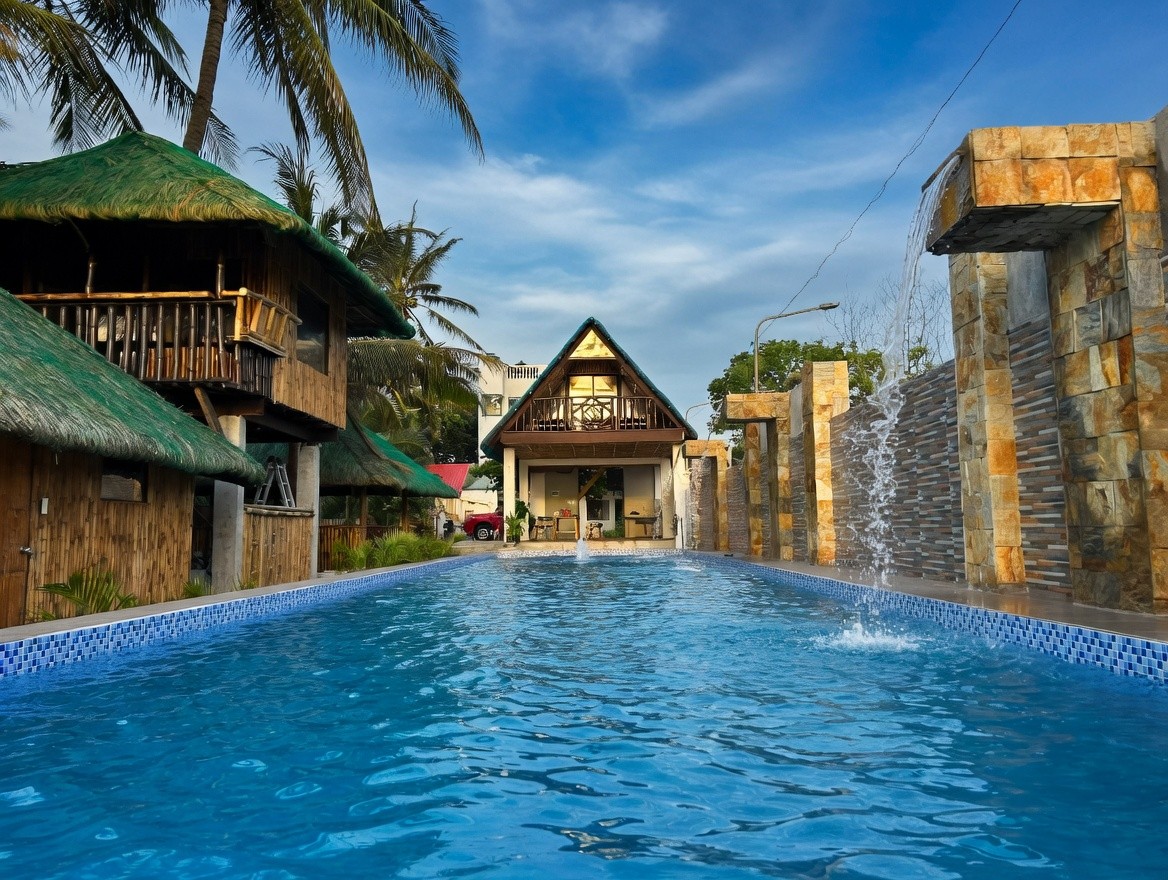 Infinity pool surrounded by palm trees and bamboo huts at Oktowaves Hotel Nasugbu