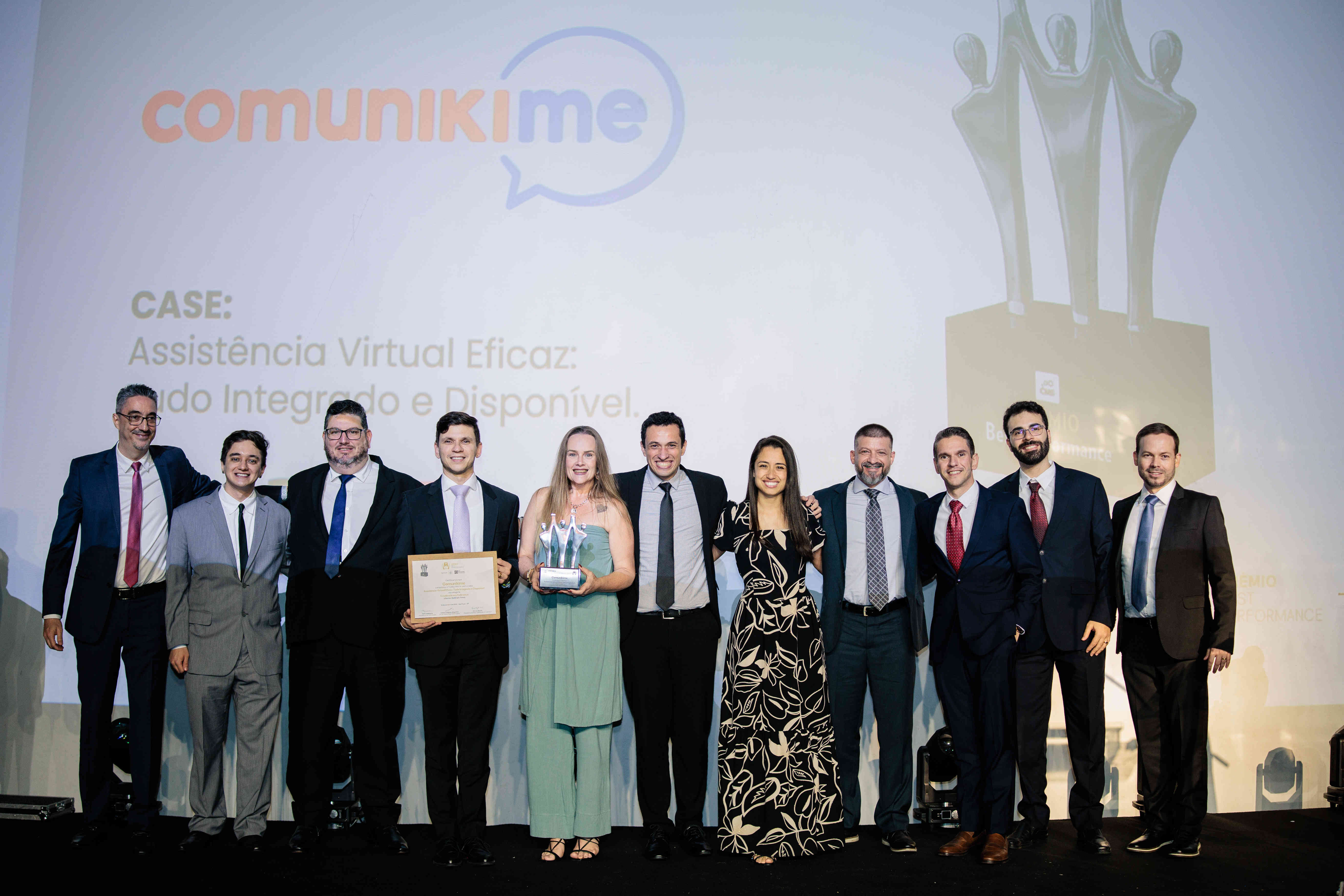 Executivos da Comunikime posando com troféu prata e certificado no palco do Prêmio Best Performance 2025