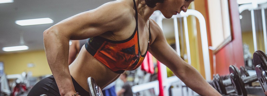 a woman leaning forward doing one arm row
