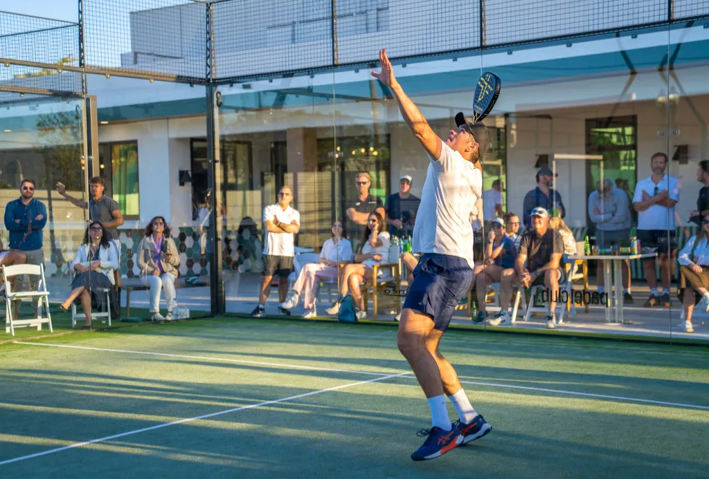 A man plays tennis on a court with spectators watching.