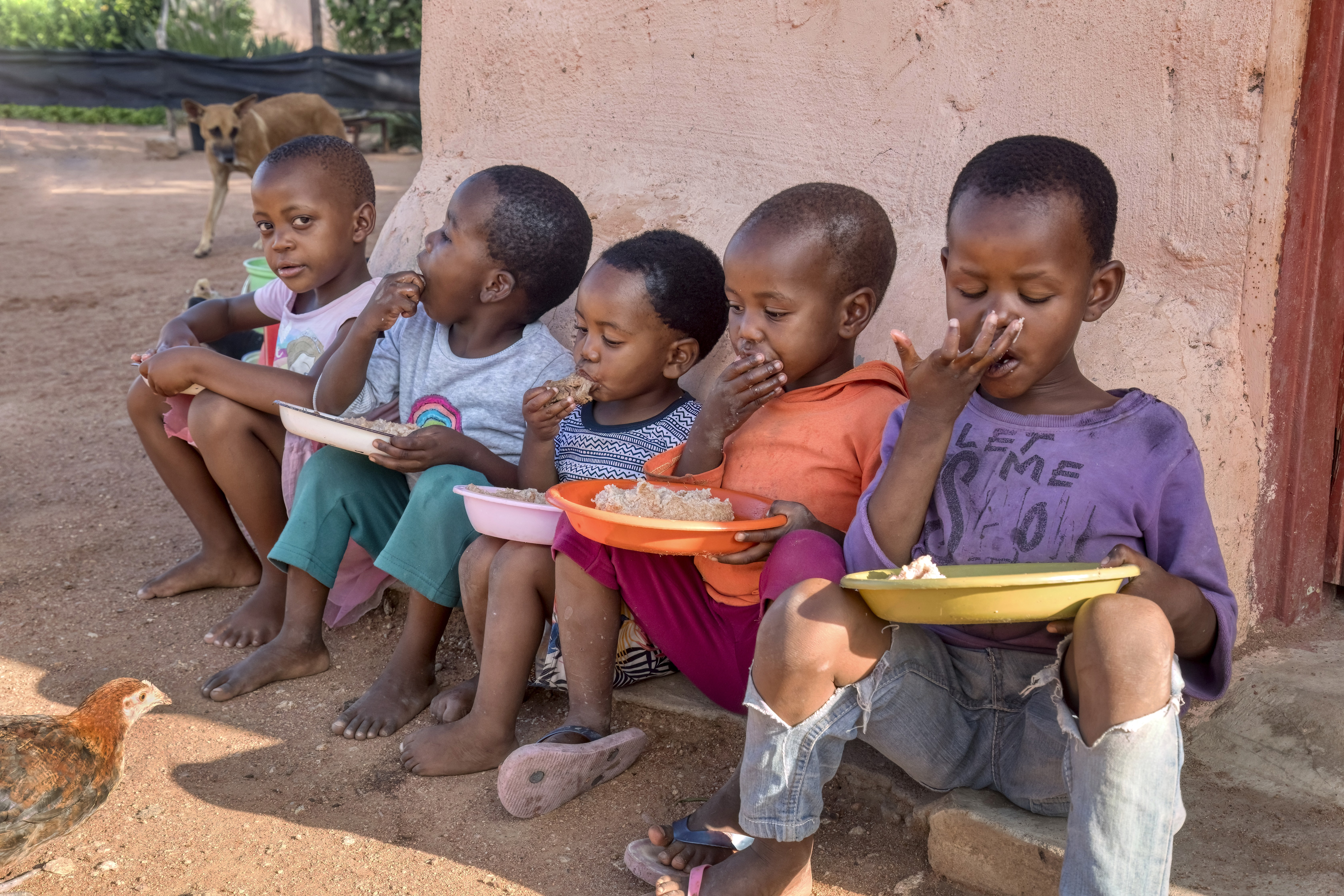 A group of cheerful Indian children in matching uniforms pose together outdoors, smiling at the camera.
