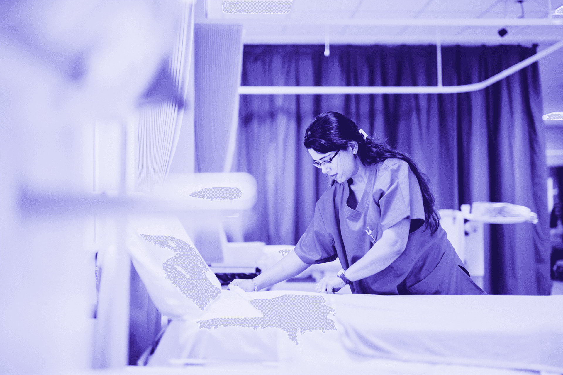 Imagem, em tons de roxo, de uma profissional da saúde arrumando uma cama de hospital.