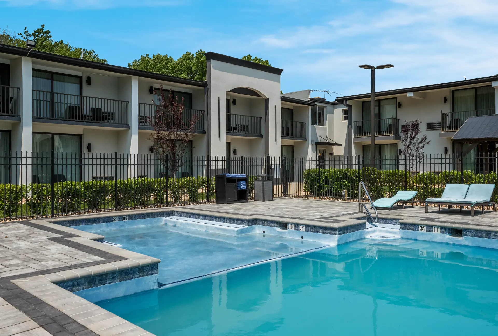 Swimming pool with lounge chairs and apartment buildings in the background.