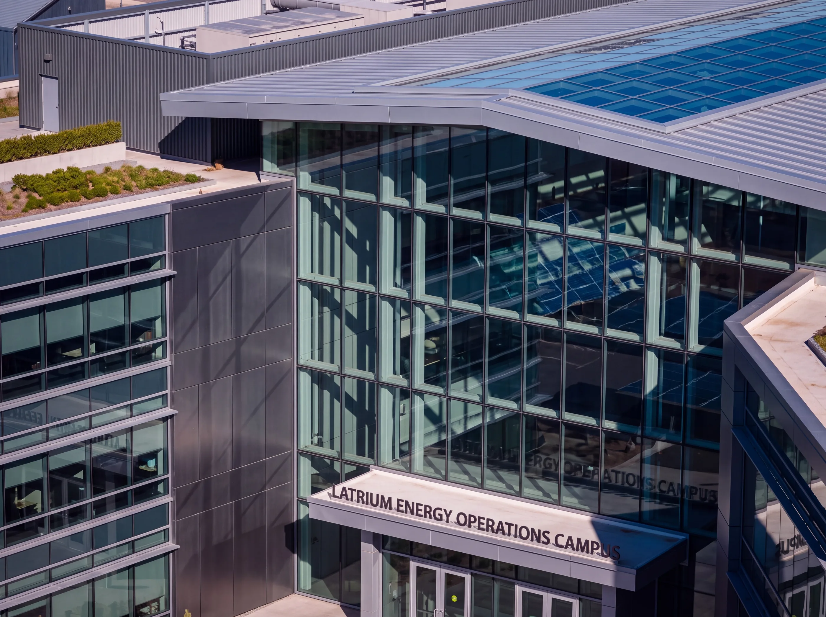 Glass and metal campus building with a green roof and entrance canopy