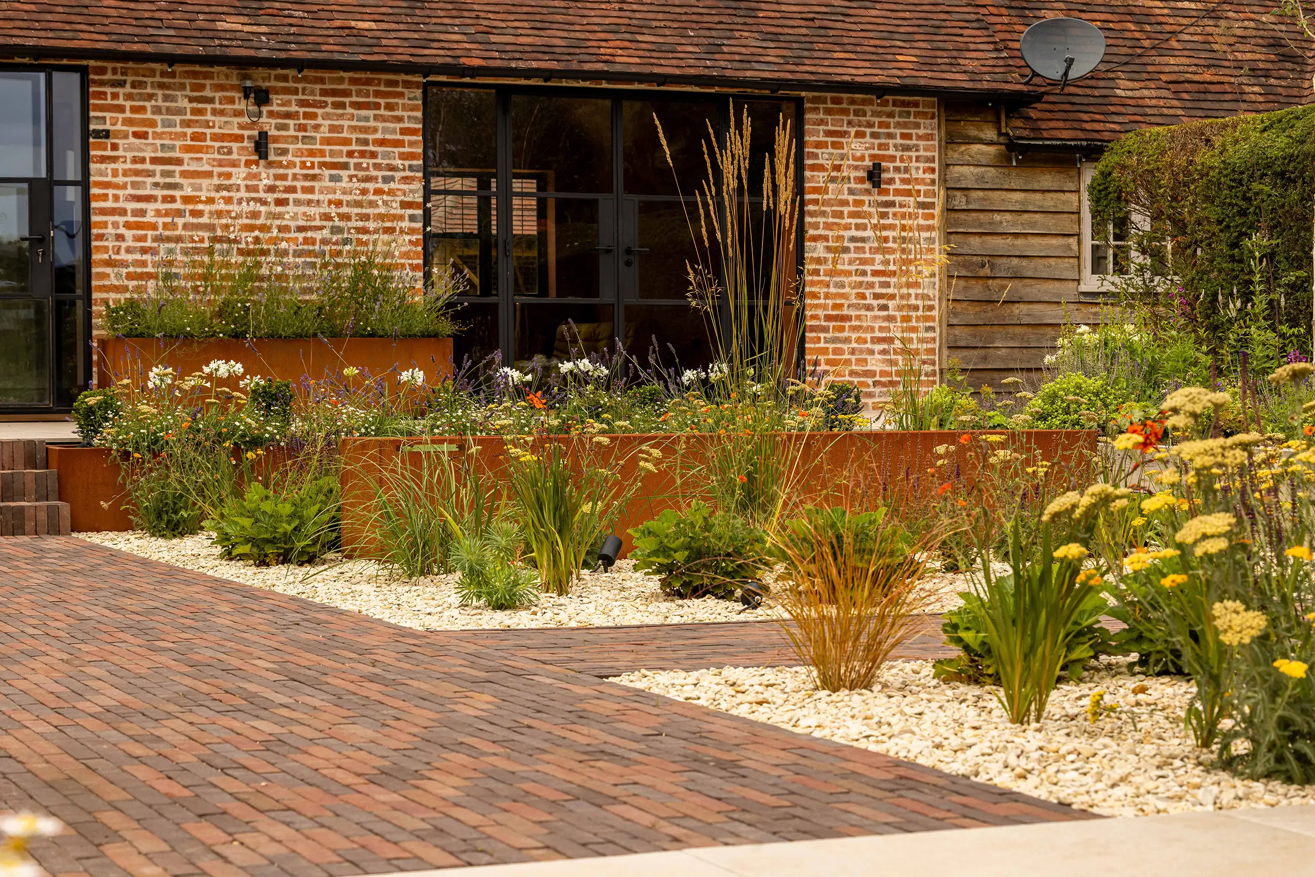 A charming house with a garden, featuring potted plants and a brick pathway leading to the entrance.