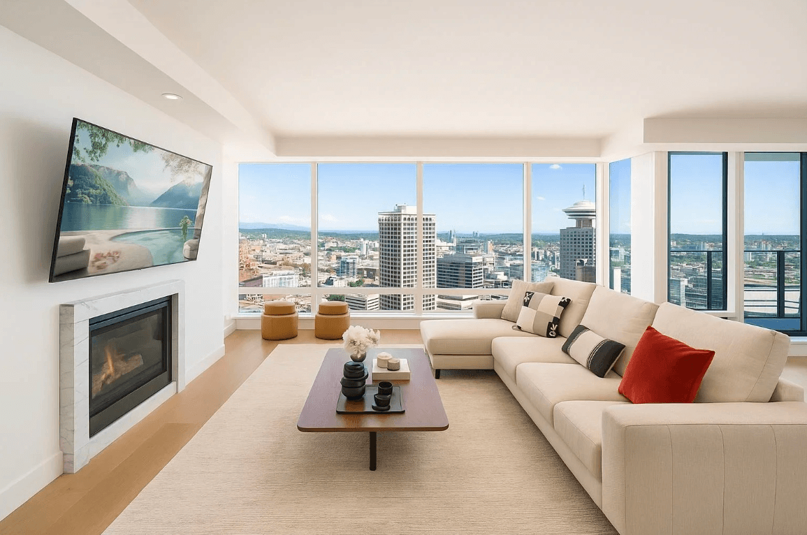 Spacious modern living room with large windows, a light sofa, a coffee table, and a TV, offering city views.