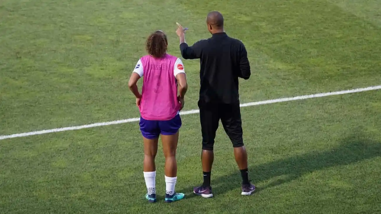 Football player receiving strategic guidance from a coach on the field.