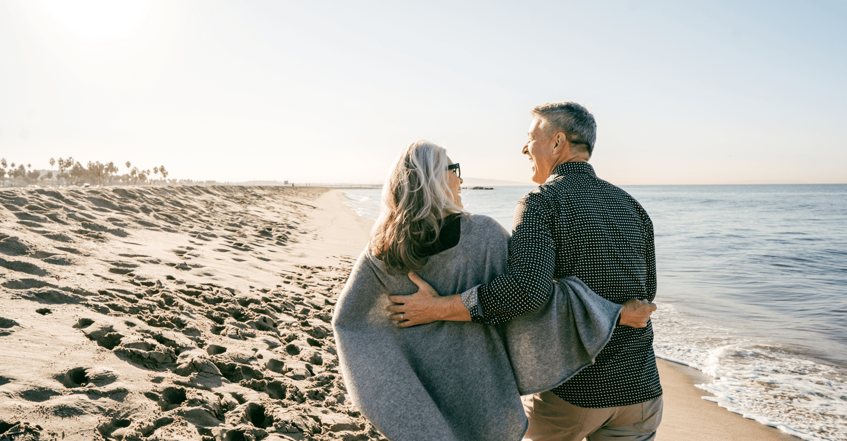 An older couple walking arm in arm along the beach, symbolising peace of mind, financial security, and protecting loved ones with trusted life insurance support.