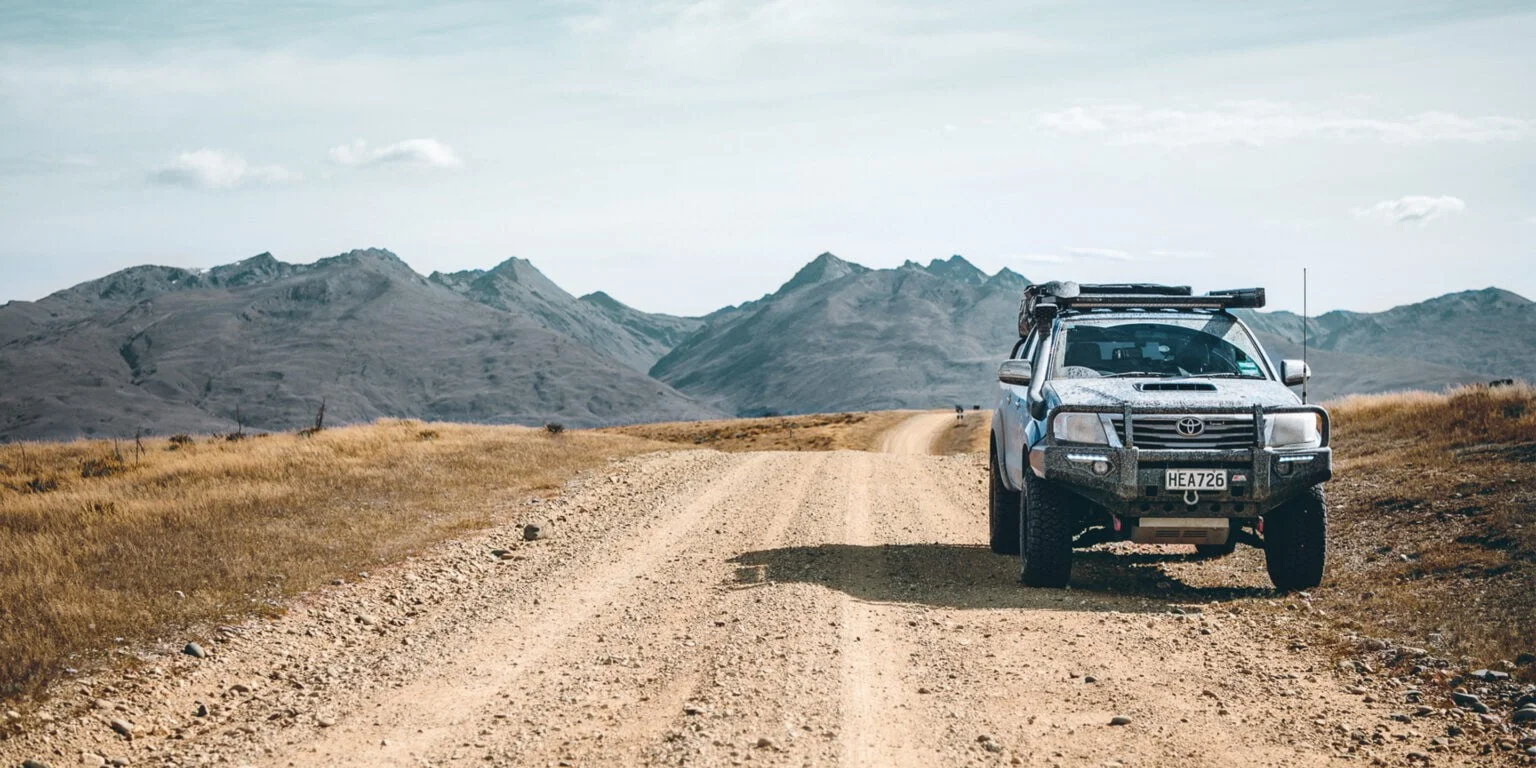 Silver 4WD parked on a remote gravel road with mountains behind, from the Ryco 'Be Ryco Ready' campaign