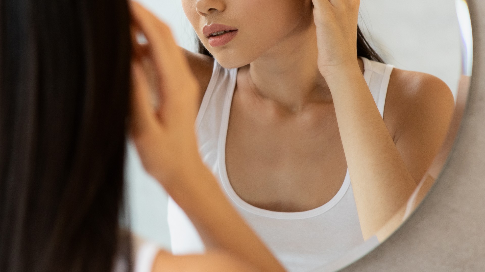 Filipina woman looking in the mirror noticing PCOS symptoms and causes