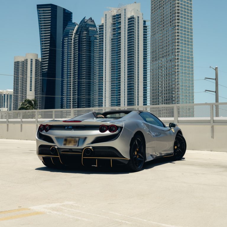 Rear 3/4 view of a silver Ferrari F8 Spyder, highlighting its iconic taillights and aggressive rear diffuser.
