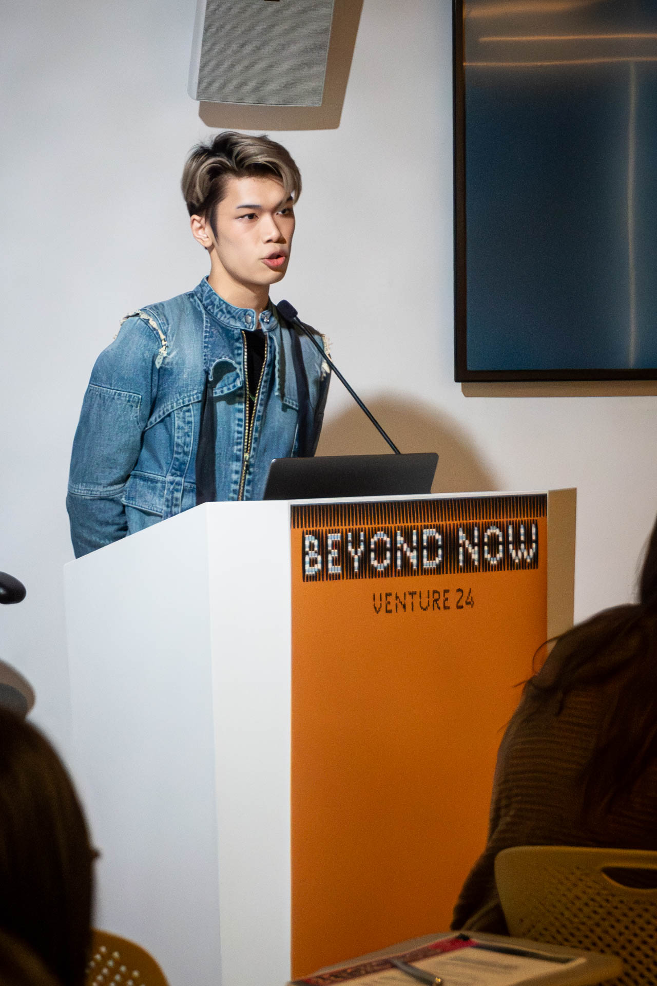 A man at the podium giving a presentation to a class.