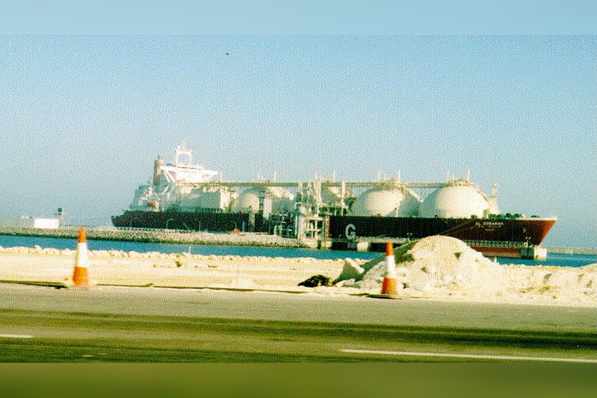 Un méthanier à quai, ses grandes cuves rondes alignées sur le pont, le type de navire qui emporte le gaz liquéfié du Qatar