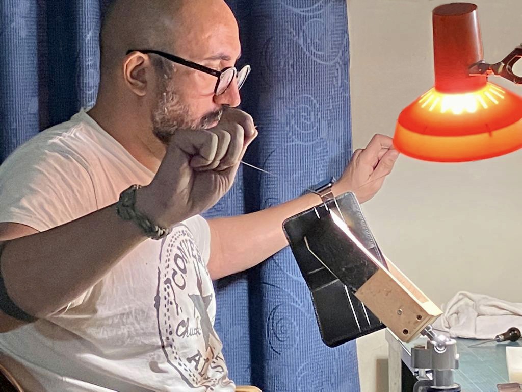 Crosstitch Leather craftsman hand-stitching a wallet in workshop