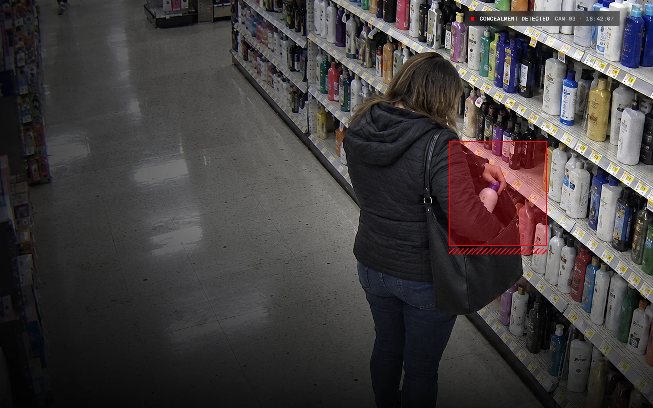 Ceiling camera view of a personal care aisle, a shopper seen from behind putting a bottle into a shoulder bag