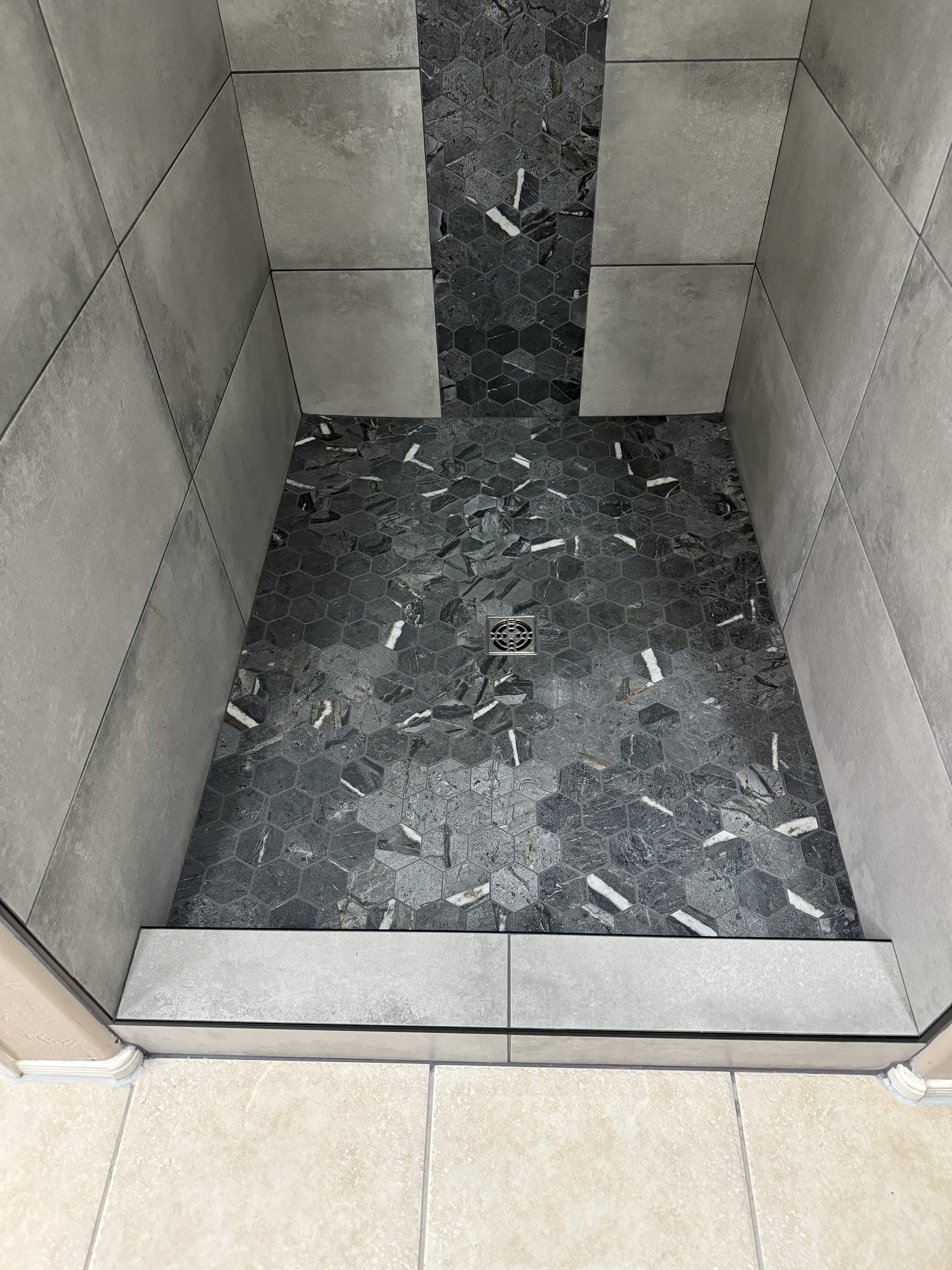 Luxurious bathroom vanity area with a dramatic wall featuring large format natural stone tiles in varying earthy tones and complex veining, serving as a striking backsplash above a double sink vanity.