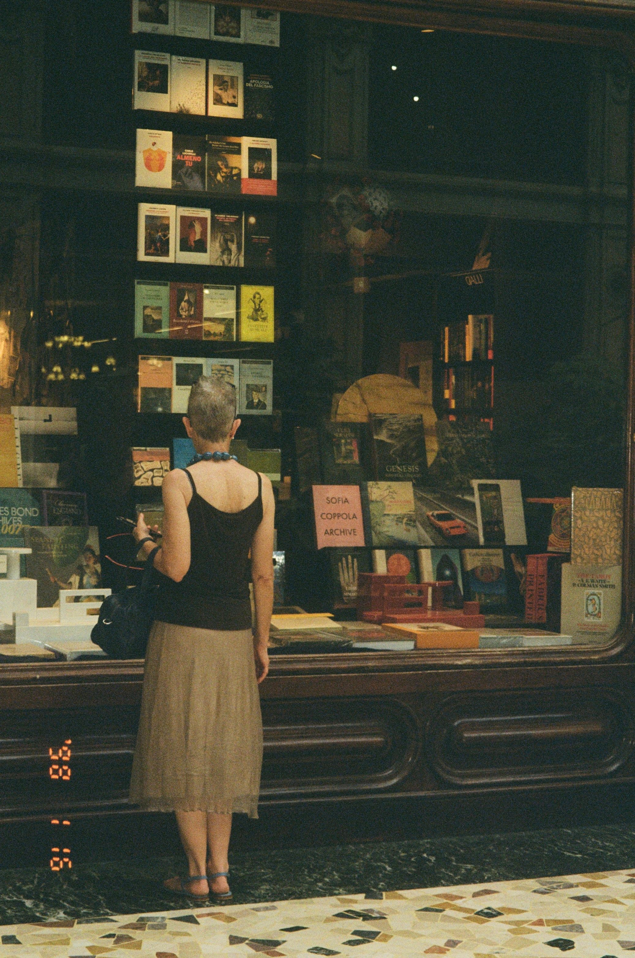 A woman browses books and objects at a bookstore display.