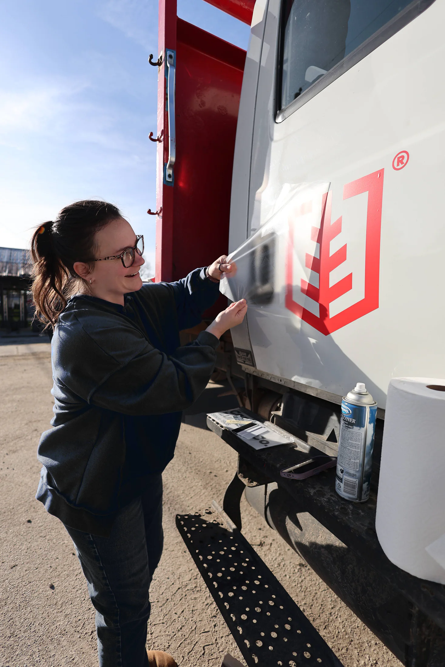Capital Lumber team member applying the red tree logo to a delivery vehicle