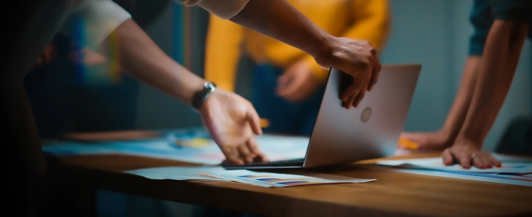 테이블 위 노트북과 자료를 놓고 여러 사람이 함께 작업하는 협업 장면