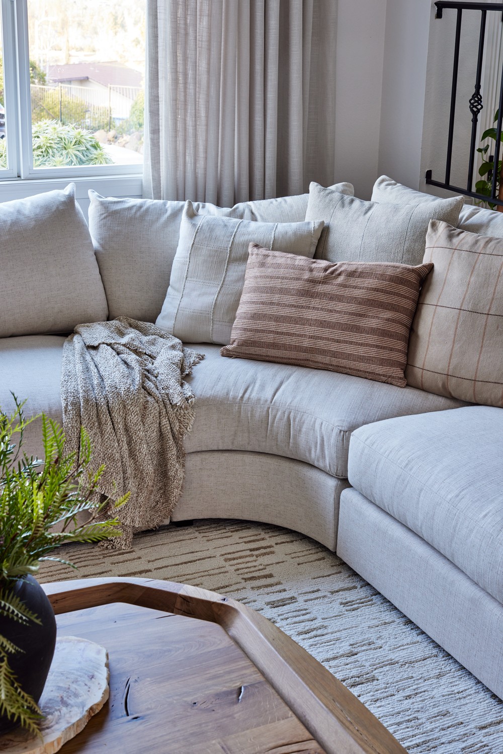 This contemporary living room features a cozy, airy atmosphere with a custom linen sofa and earthy wooden accents