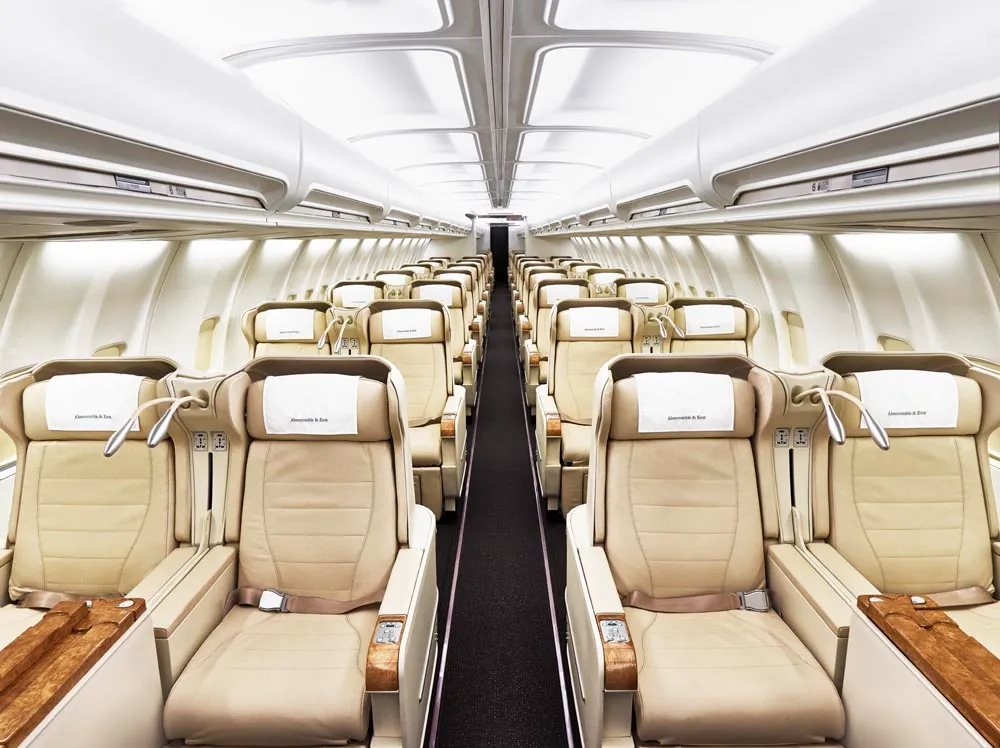 Wide premium private jet cabin with cream leather seats