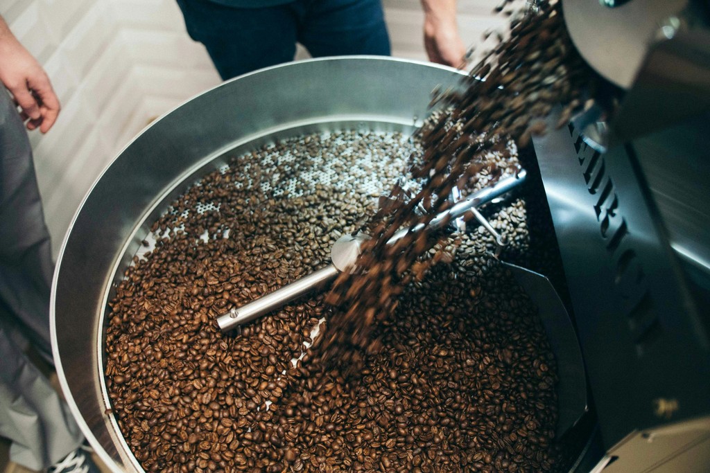 A coffee roasting machine dumping freshly roasted beans ready for brewing.