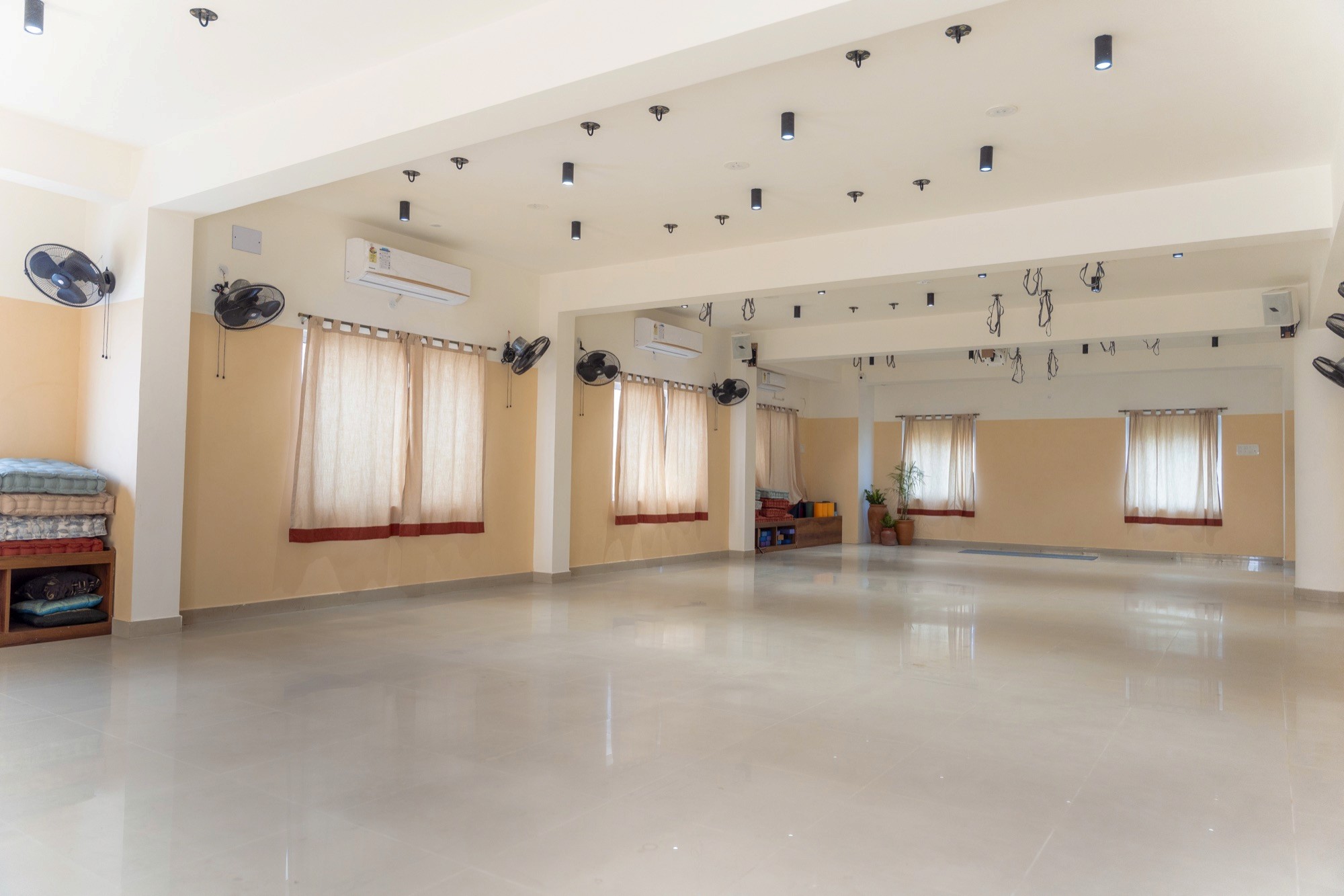 The empty Chennai Yoga Studio hall with large windows and a polished floor