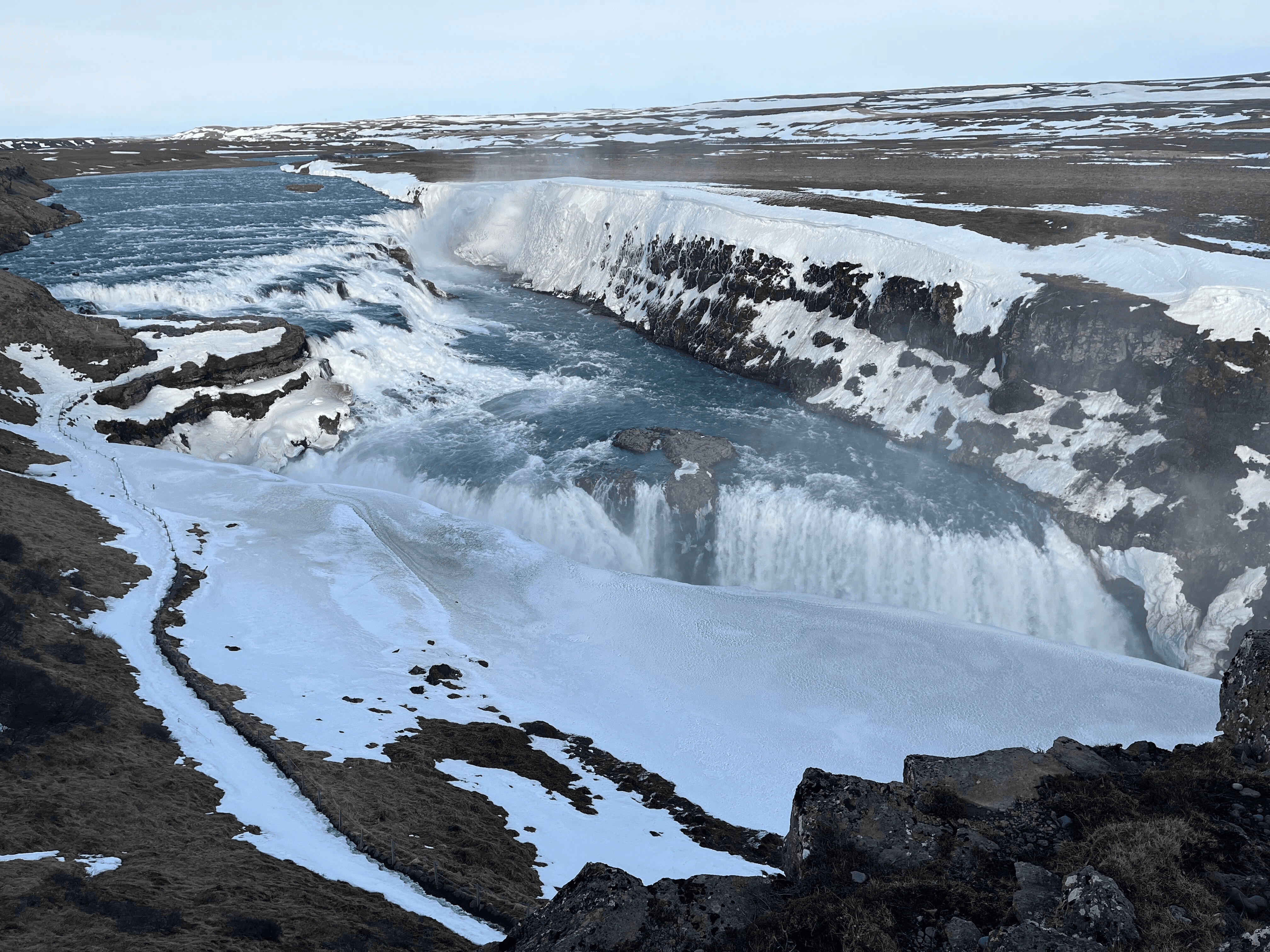 A powerful Icelandic waterfall cascading over icy rocks.