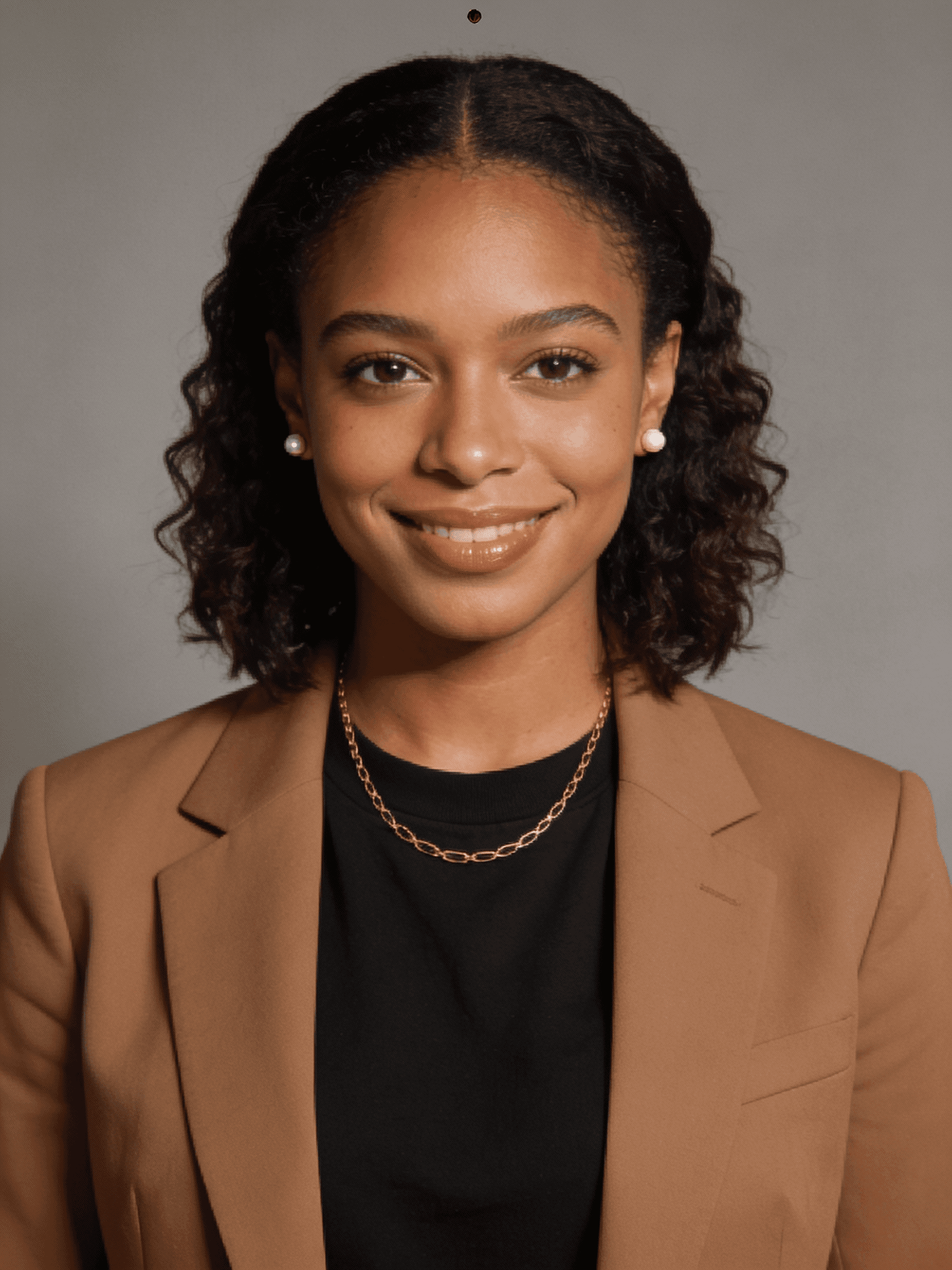 Professional portrait of a woman with short curly hair, wearing a black blazer, against a neutral background.