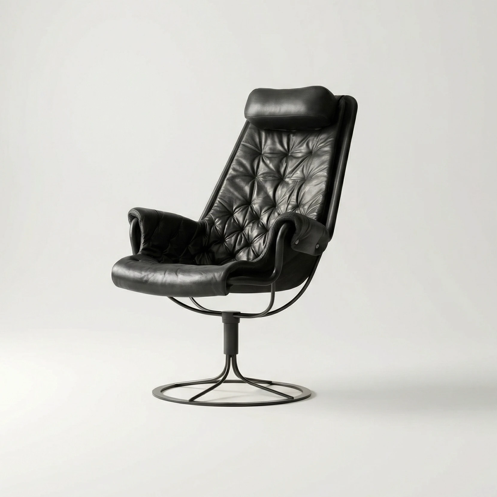 A smiling person with curly hair sits at a desk, looking at a laptop against a dark background.