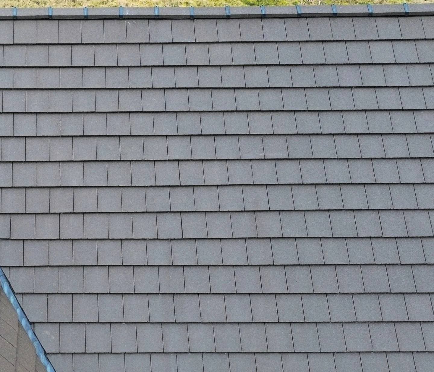 Close-up of a gray shingle roof with evenly aligned rectangular tiles.