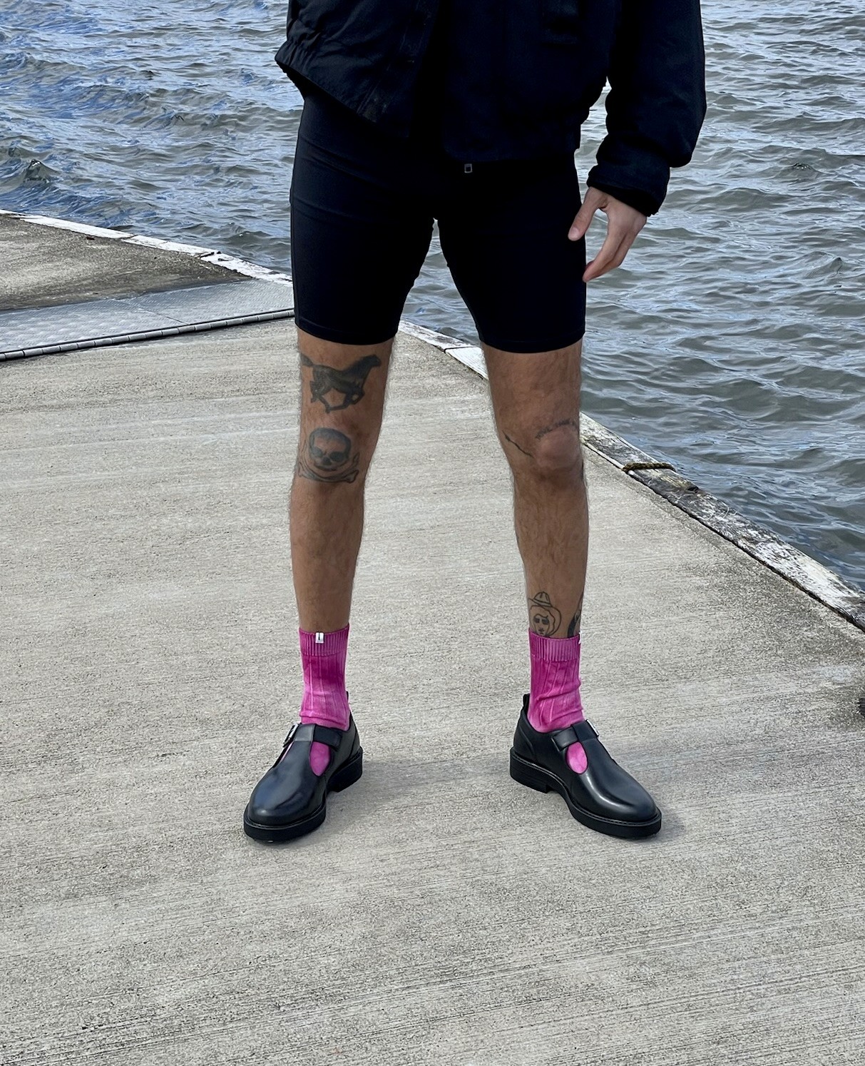 Le bas du corps d'un homme qui porte un cycliste, des sandales et noires et des chaussettes fuschia