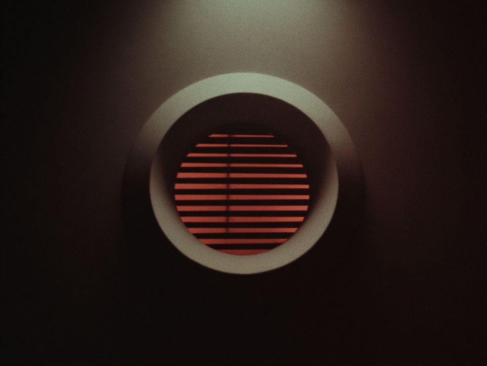 Retro-style coral pink portable speaker with horizontal grille lines on dark surface