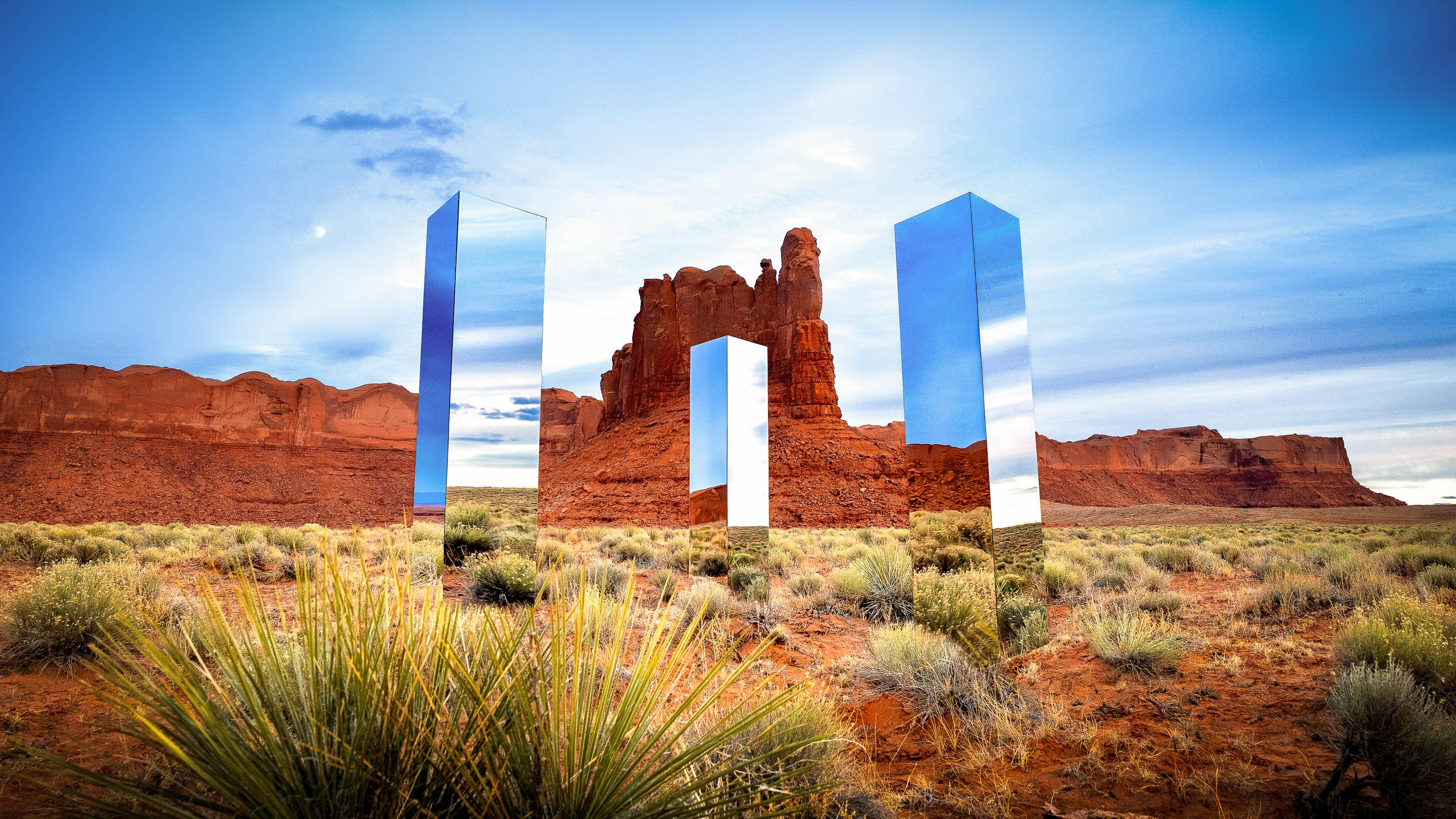 Three mirror monoliths in front of giant Arizona red rocks that were designed by creative director Owen Brown