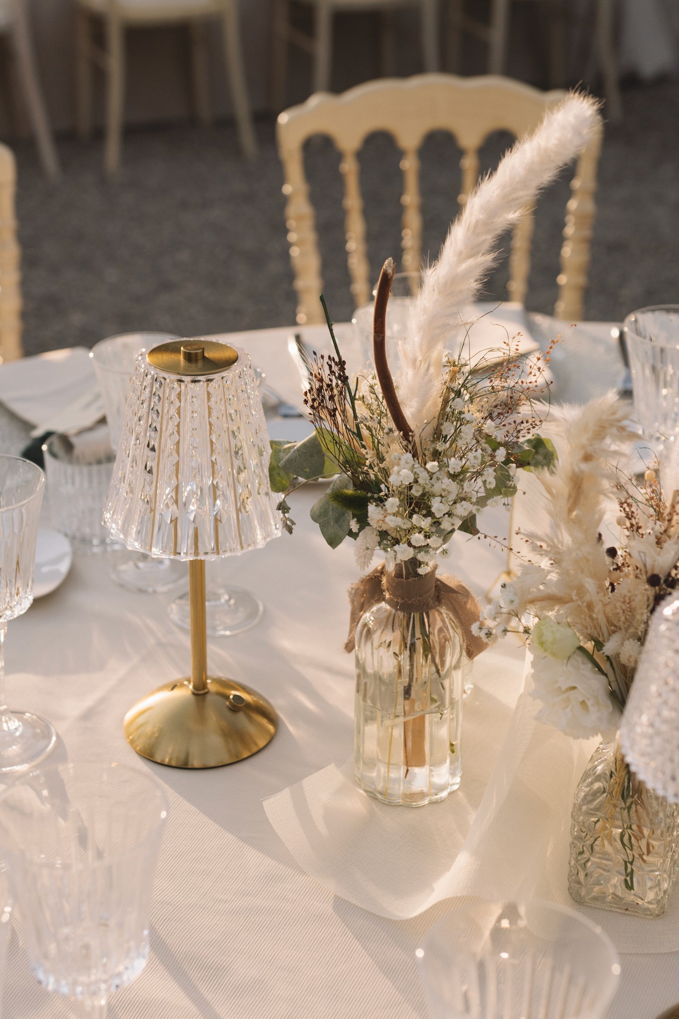 Centrotavola matrimonio con piumetta bianca e fiori secchi, tavolo ricevimento al Parco di Montebello, sedie chiavari dorate